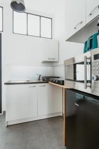 a kitchen with white cabinets and a black refrigerator at Studio - Normandy 1 in Le Havre