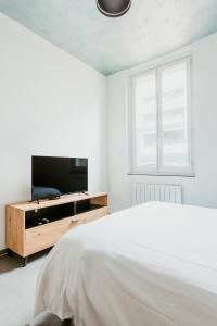 a white bedroom with a bed and a television at Studio - Normandy 1 in Le Havre