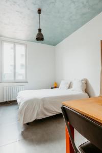 a white bedroom with a bed and a table at Studio - Normandy 1 in Le Havre