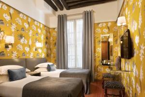a hotel room with two beds and yellow wallpaper at Hôtel Saint-Paul Rive-Gauche in Paris