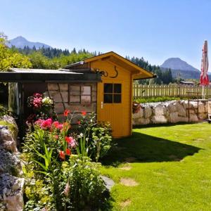 a small yellow shed in a yard with flowers at Haus Hubertus in Hochfilzen