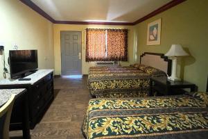a hotel room with two beds and a flat screen tv at Sun Star Inn Los Banos in Los Banos