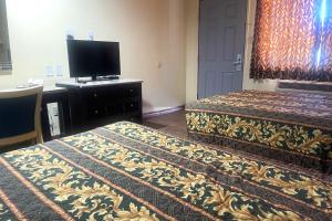 a hotel room with two beds and a flat screen tv at Sun Star Inn Los Banos in Los Banos