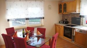 a kitchen with a glass table and red chairs at Ferienhaus am Flaumbach in Blankenrath