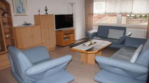 a living room with blue chairs and a table and a tv at Ferienhaus am Flaumbach in Blankenrath +29 photos