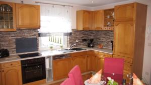 a kitchen with wooden cabinets and a table with pink chairs at Ferienhaus am Flaumbach in Blankenrath