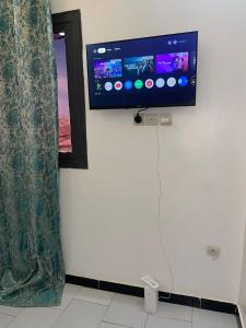a flat screen tv on a wall in a room at Résidence KUYITO in Kaolack