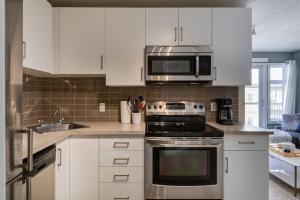 a kitchen with white cabinets and a stove and microwave at Stylish Mountain View Condo with Gym in Canmore
