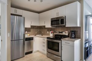 a kitchen with white cabinets and a stainless steel refrigerator at Stylish Mountain View Condo with Gym in Canmore +24 photos