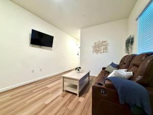 a living room with a couch and a tv on a wall at Attached Guest House in Woodland