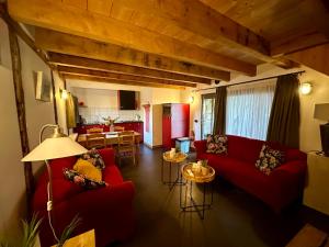 a living room with red couches and a kitchen at Erfgoed & Logies Den Heijkant in Moergestel