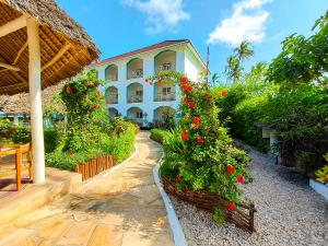 a building with red flowers in a garden at AHG Sun Bay Mlilile Beach Hotel in Matemwe