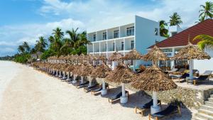 a row of straw umbrellas and chairs on a beach at AHG Sun Bay Mlilile Beach Hotel in Matemwe +65 photos