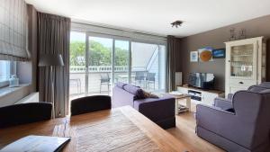 a living room with purple furniture and a balcony at Duinhof in Cadzand-Bad