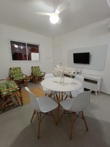 a white dining room with a white table and chairs at Boracéia Apto 1 quarto in Bertioga
