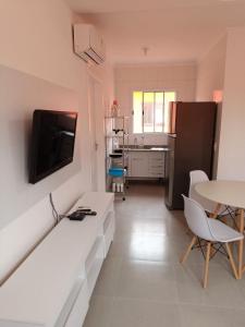 a living room with a table and a tv on a wall at Boracéia Apto 1 quarto in Bertioga +6 photos