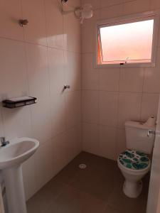 a bathroom with a toilet and a sink and a window at Boracéia Apto 1 quarto in Bertioga