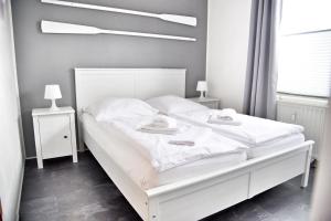 a white bed in a bedroom with two night stands at Lagunenstadt am Haff - Fewo 34 Palstek in Ueckermünde