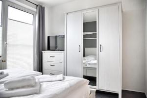 a white bedroom with two beds and a mirror at Lagunenstadt am Haff - Fewo 34 Palstek in Ueckermünde