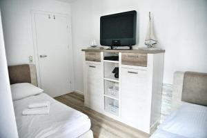 a living room with a tv on a white cabinet at Lagunenstadt am Haff - 119 Marina in Ueckermünde +16 photos