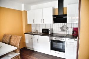 a kitchen with white cabinets and a microwave at Lagunenstadt am Haff - 133 Hol über! in Ueckermünde