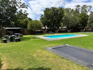 a pool with picnic tables and benches in a yard at De Rust Private Nature Reserve in Odendaalsrus