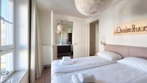 a white bedroom with a large bed and a chandelier at Duinhof in Cadzand-Bad