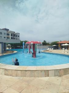 a pool with a red umbrella and people in it at Cumbuco Geek House in Cumbuco