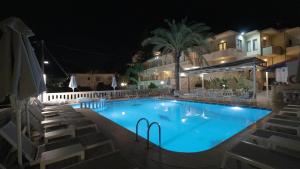 a swimming pool at night with chairs around it at Amaryllis in Platanias