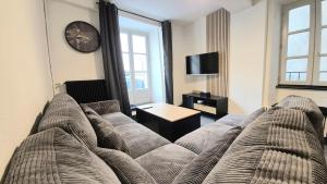 a living room with a couch and a clock on the wall at Le Passage - Centre-ville - WiFi in Issoire