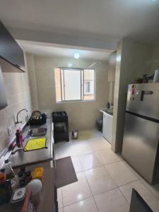 a kitchen with a stainless steel refrigerator and a tile floor at Quarto em Apartamento na Trindade in Florianópolis