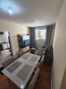 a room with two beds and a table and a television at Quarto em Apartamento na Trindade in Florianópolis