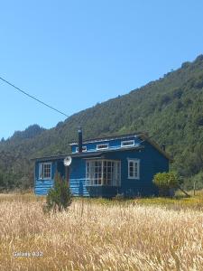 a blue house in the middle of a field at Cabaña Terraza del Yates in Puerto del Yate +8 photos