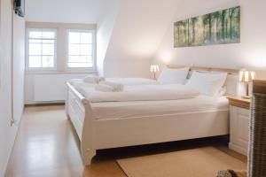 a bedroom with a large white bed with white sheets at Ferienhof Werner in Emstek