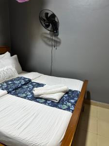 a bed with two towels and a fan on the wall at Ekinot homes in Lira