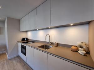 a kitchen with white cabinets and a sink at LÖYLY Egmond in Egmond aan Zee