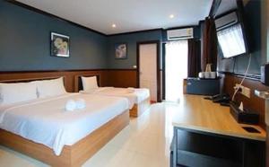 a bedroom with two beds and a flat screen tv at THE BRETON Hotel in Ban O Pao