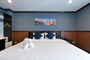 a bedroom with a white bed with two stuffed animals on it at THE BRETON Hotel in Ban O Pao