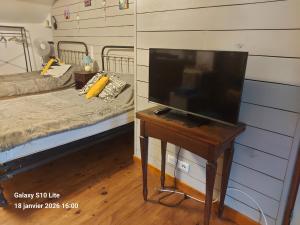 ein Fernseher auf einem Tisch in einem Schlafzimmer mit einem Bett in der Unterkunft La Tignoise in Tignac