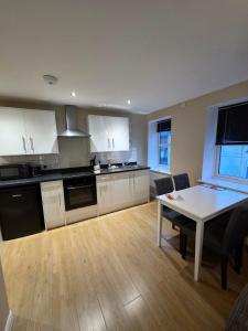 a kitchen with white cabinets and a table and a dining room at 4b Smart Apartments in Newark-on-Trent +55 photos