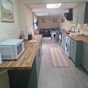 a kitchen with a microwave on top of a counter at Clover Crest - 3-Bedroom House in Bourton on the Water