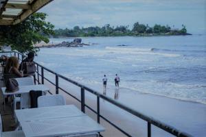 two people walking in the water on the beach at Hôtel Copacabana Kribi in Kribi