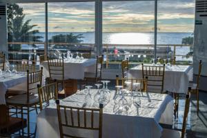 a restaurant with white tables and chairs with a view of the ocean at Hôtel Copacabana Kribi in Kribi