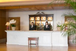 zwei Frauen stehen an einem Tresen in der Hotellobby in der Unterkunft Hotel Grand Tiara Minaminagoya in Anjomachi