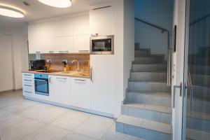 a kitchen with white cabinets and a staircase at Jiná báseň in Pustá Rybná +19 photos