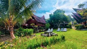 a yard with a table and chairs and a house at Leokap Homestay in Tuktuk Siadong