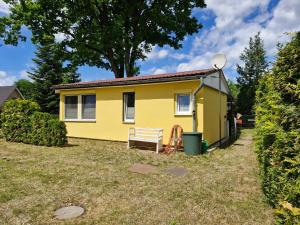 a yellow tiny house with a bench in the yard at Ferienhaus Marc in Göhren-Lebbin