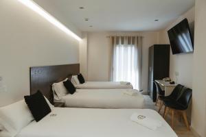 a hotel room with two beds and a television at Imprenta Musical Alojamiento in Astorga