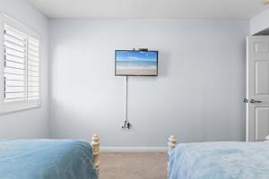 a room with two beds and a tv on the wall at Dune Pointe 402 - Shells, Surf & Sea Turtles in Fort Walton Beach