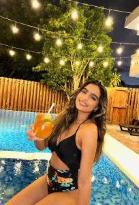 a woman in a bikini holding a drink by a pool at Casa Docia Hotel in Santa Bárbara de Samaná